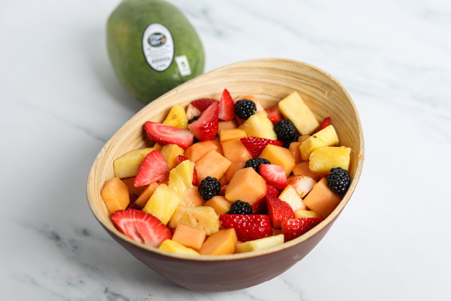 Image of fruit salad in wood bowl with Royal Star papaya in background