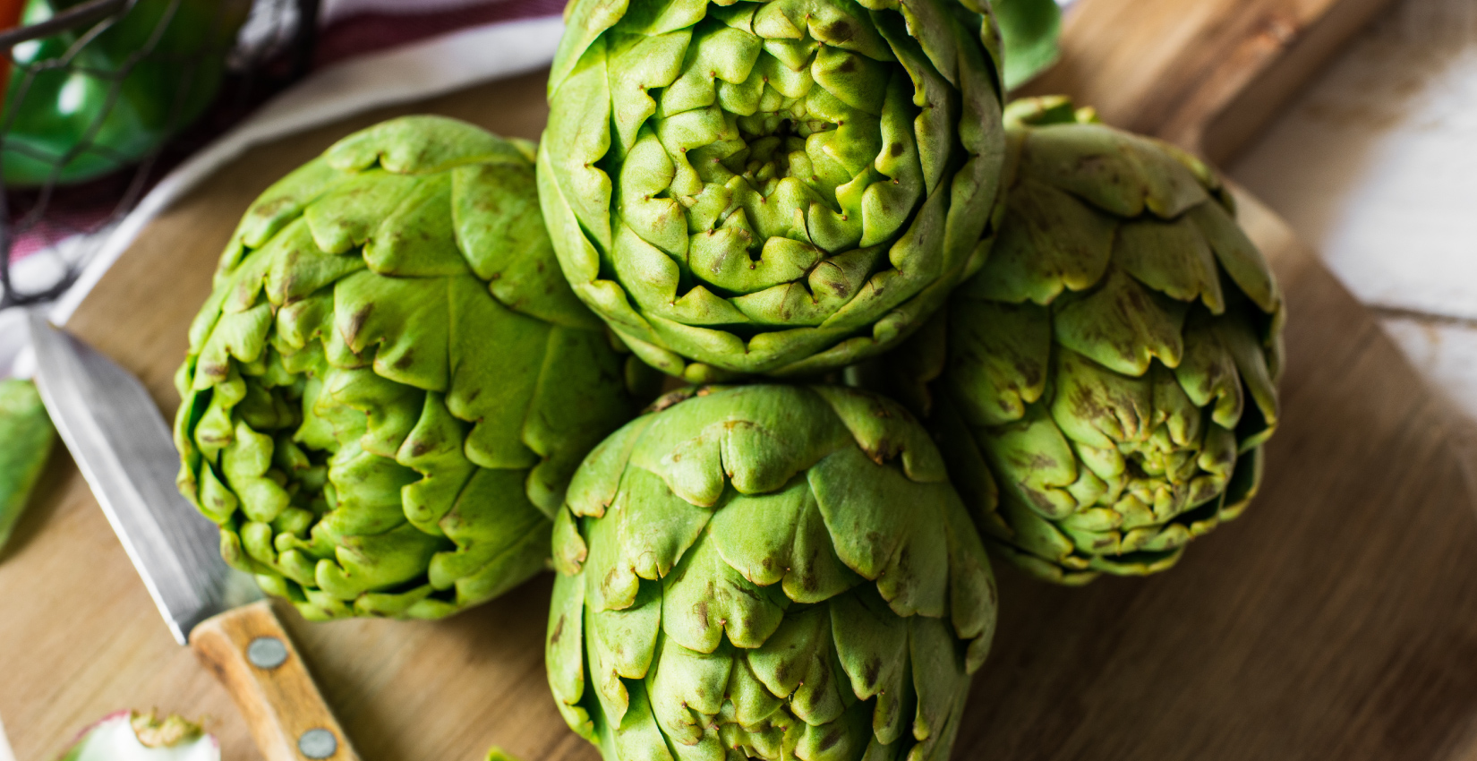 an image of four artichokes stacked on a cutting board